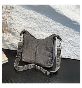 Detailed macro view of dark grey washed denim fabric and wide strap on the retro hobo bag
