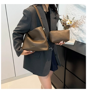 Detail view of brown leather bucket bag and pouch set with golden logo and soft texture