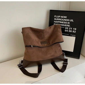 Detail of dark brown tote bag showing mixed matte and smooth leather textures and silver buckle
