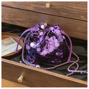 Dettaglio borsa a secchiello in paillettes viola con tracolla a catena e chiusura a coulisse