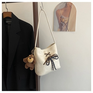 Detail of cream suede bucket bag with blue polka dot bow and plush dog charm