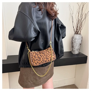 Close-up of leopard print baguette bag with gold chain and adjustable brown leather strap