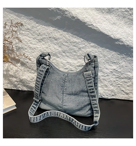 Detail of dark blue denim hobo bag on stone surface with retro artistic texture