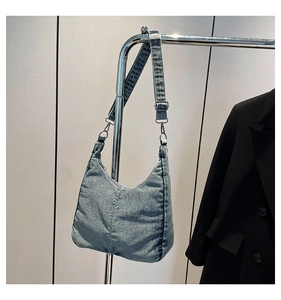 Detail of vintage blue washed denim hobo bag featuring contrast stitching and adjustable strap