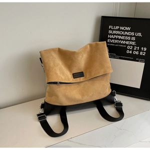 Detail of camel suede tote bag with black strap and metallic buckle in a studio setting