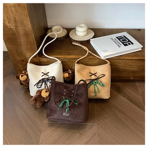 Three suede bucket bags with ribbon bows and cute bear charms in a warm home setting