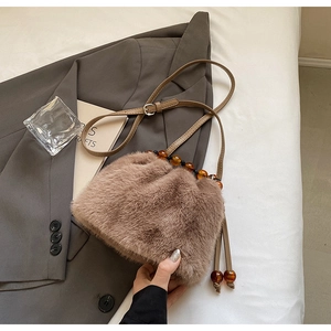 Detailed close-up of brown faux fur bucket bag with amber beads and leather shoulder strap