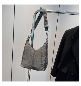 Detail of grey washed denim hobo bag fabric texture and silver hardware on shoulder strap