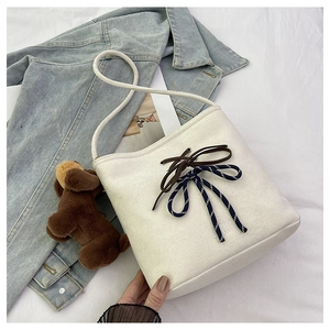 Detail of cream suede bucket bag featuring double bows and Valila embroidered logo