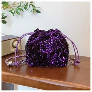 Dettaglio borsa a secchiello con paillettes viola e catena in metallo su legno