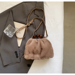 Detail of leopard faux fur bucket bag with amber beaded handle and leather strap