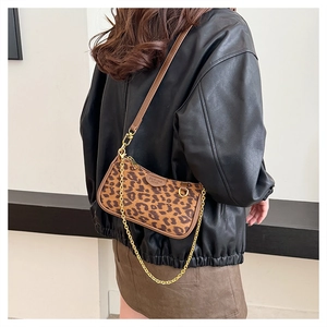 Detail of leopard print crossbody bag with gold chain strap and brown trim on a leather jacket