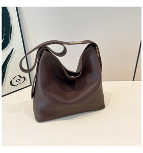 Detail of soft dark brown leather tote bag with matte finish and gold hardware buckles