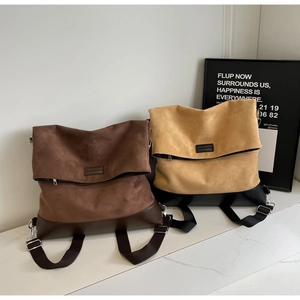 Detail of dark coffee and khaki suede backpacks with leather patchwork and metal buckles
