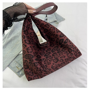 Macro detail of red-brown leopard print fabric and faux leather handle on a tote bag