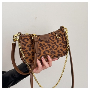 Detailed close-up of leopard print fabric with luxury gold chain and leather strap