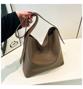 Detail of soft dark brown hobo tote bag featuring a wide strap and minimalist gold logo
