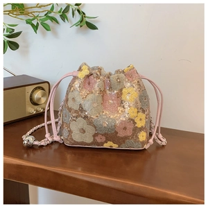 Dettaglio ravvicinato della borsa a secchiello rosa con paillettes floreali e catena