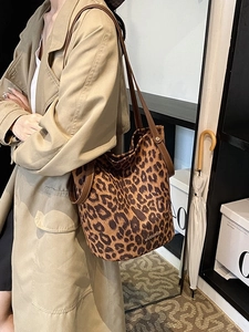 Chic leopard print suede bucket bag with leather straps worn by model in trench coat