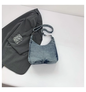 Detail of vintage washed denim hobo shoulder bag with metal hook and strap texture