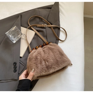 Detail of faux mink fur crossbody bag with amber-textured beads and leather strap