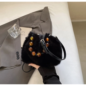 Detail of black faux fur bucket bag featuring amber acrylic bead and sleek leather strap