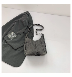 Detail of vintage grey washed denim hobo bag with adjustable strap and silver metal hardware