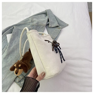Detail of canvas bucket bag with cotton rope strap and brown plush dog pendant