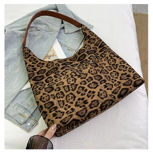 Flat lay of leopard print tote bag with brown leather straps on casual lifestyle background