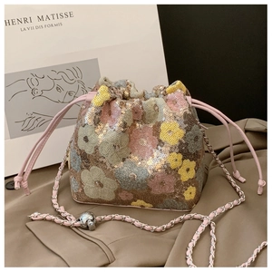 Dettaglio borsa a secchiello con paillettes floreali e catena argento su tessuto marrone