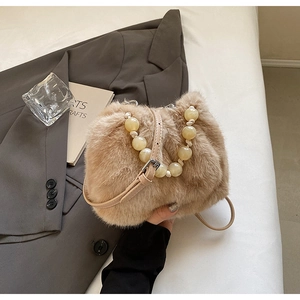 Close-up of faux mink fur bucket bag with pearl handle and leather shoulder strap detail
