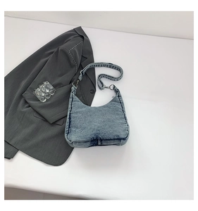 Close-up of vintage washed blue denim hobo bag texture and adjustable strap hardware