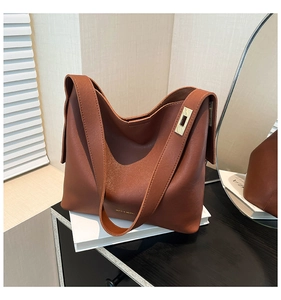 Detail showing high-quality caramel leather texture and golden metal buckle on bucket bag