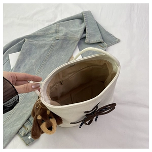 Top view of bucket bag interior showing magnetic closure, zipper pocket and plush dog charm