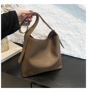 Detailed view of brown matte leather bucket bag with wide shoulder strap and refined texture