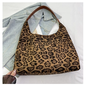 Detail of leopard print tote bag with brown leather handles on denim jacket