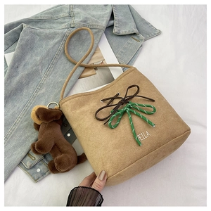 Detail of suede bucket bag with embroidered VEILA logo and plush puppy charm