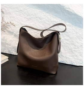 Detailed macro view of dark brown leather texture and golden logo on a stylish tote bag