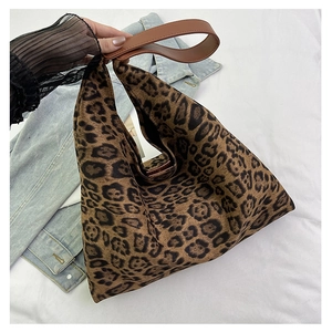 Detail shot of leopard print tote bag with brown leather handles and canvas texture