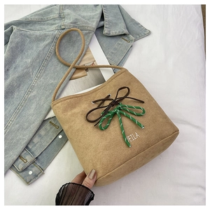 Close-up of khaki suede bucket bag featuring bow knot detail and VEILA embroidery