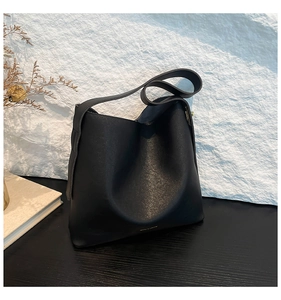 Close-up of black matte grain leather bucket bag with elegant golden hardware details