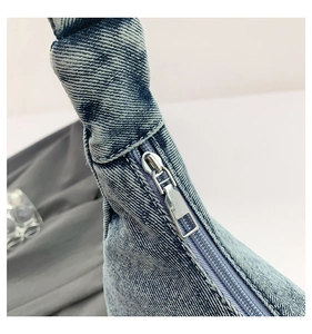 Detail shot of light blue denim fabric texture and smooth silver metal zipper on bag