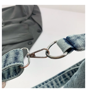 Detail of blue denim shoulder strap with silver metal lobster clasp on a vintage bag