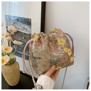 Dettaglio della borsa a secchiello con paillettes floreali e tracolla a catena in metallo