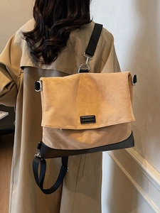 Minimalist khaki suede tote bag with black strap worn over a light brown trench coat