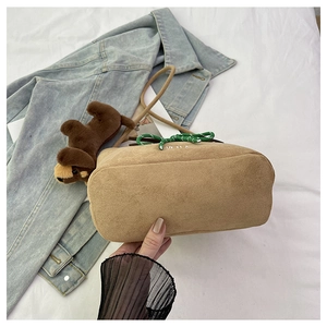 Detail of khaki suede bucket bag featuring green woven drawstring and white YTLIA embroidery