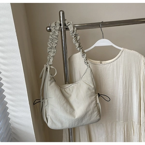 Detail van de lichtbeige cloud bag met geplooide textuur en verstelbare trekkoorden