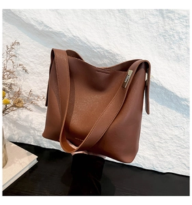 Detail view of brown faux leather tote bag with wide strap and gold hardware accents