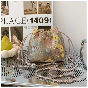 Dettaglio della borsa a secchiello con paillettes floreali, coulisse rosa e tracolla a catena