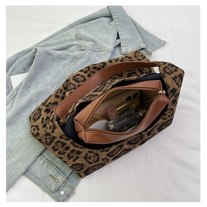 Detail view of large leopard tote bag with brown inner pouch holding makeup and phone